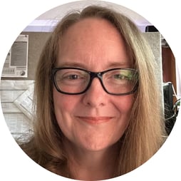 Sue is smiling. She wears dark glasses and her light brown hair is framing her face.
